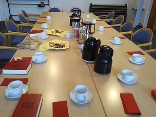 Foto eines mit Kaffeetassen, Kaffeekannen und Gebäck gedeckten Tisches