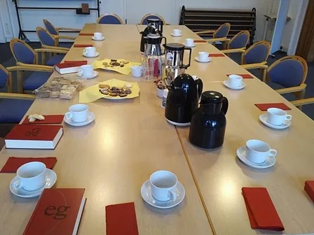Foto eines mit Kaffeetassen, Kaffeekannen und Gebäck gedeckten Tisches