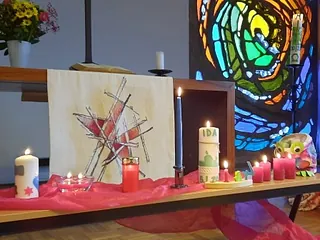 Foto Taufkerzen auf einer Bank, Altar und Fenster der Lichtenplatzer Kapelle im Hintergrund